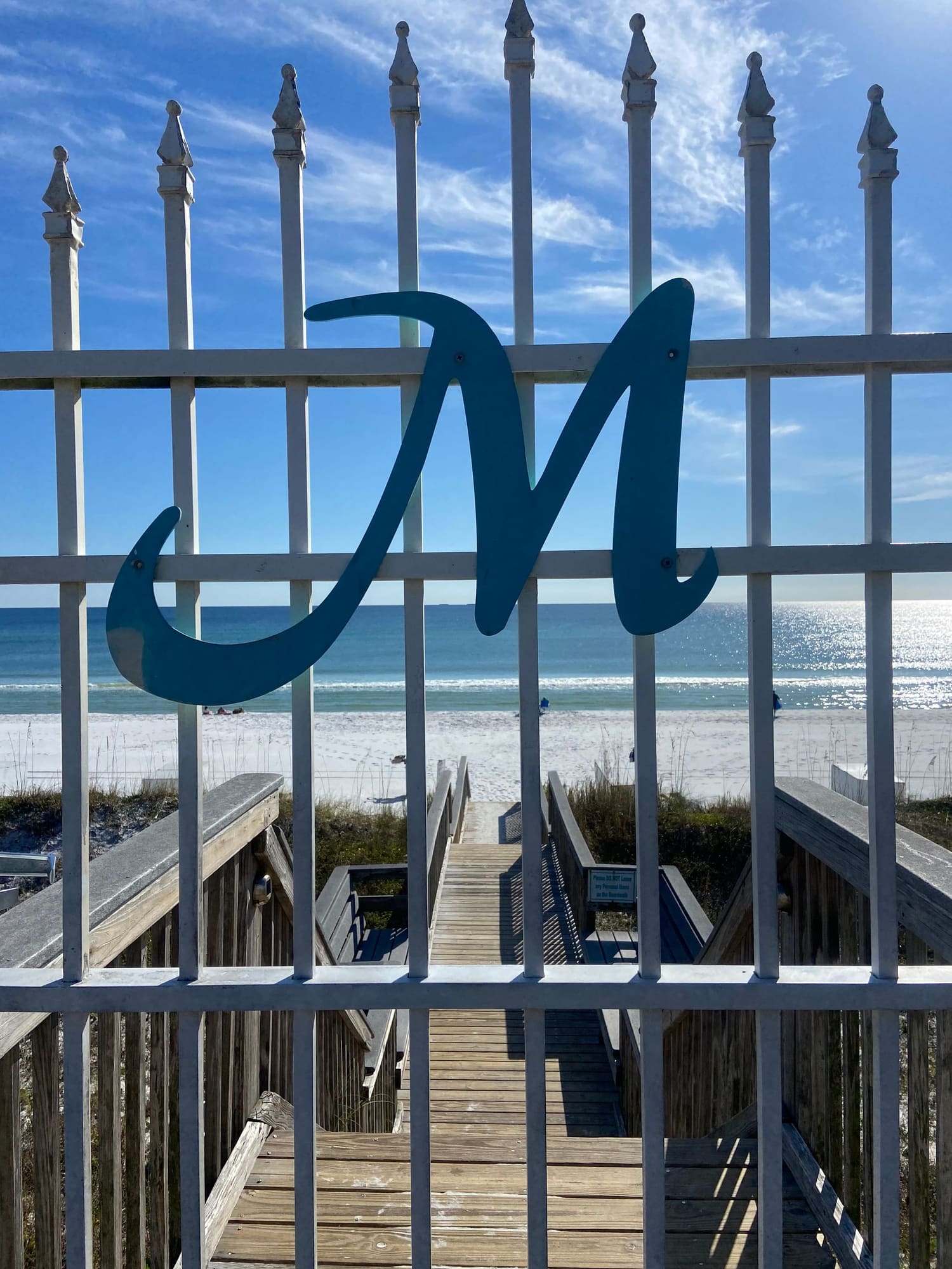 Blue decorative gate with wave design overlooking beach boardwalk and ocean